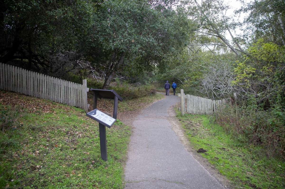 Dos excursionistas pasan junto a una valla a lo largo de Earthquake Trail.