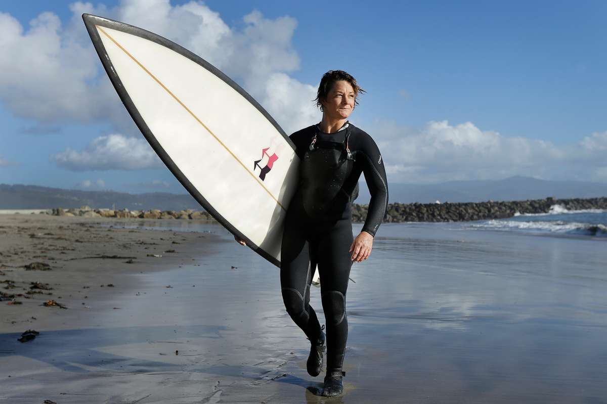Bianca Valenti camina por la playa después de surfear olas en Mavericks en Half Moon Bay, California.
