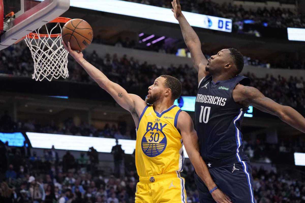 El escolta de los Golden State Warriors, Stephen Curry (30), vuelve a hacer una bandeja al alero de los Dallas Mavericks, Dorian Finney-Smith (10), durante la segunda mitad de un juego de baloncesto de la NBA en Dallas, el miércoles 5 de enero de 2022.