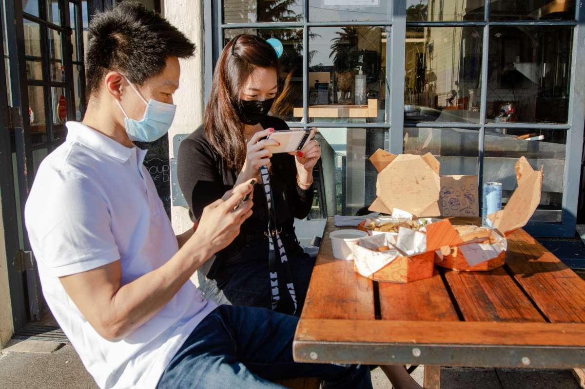 Los clientes Johnson Hsieh (izquierda) y Shelley Chang fotografían su pedido en los asientos al aire libre del restaurante de comida para llevar Grégoire en Berkeley, California, el 12 de enero de 2022.