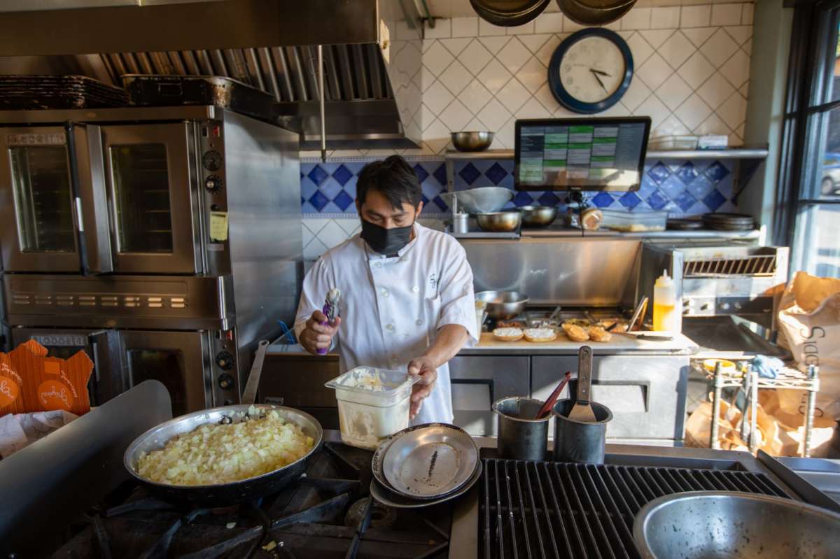 El cocinero Isiaias Alvarez prepara un pedido en la cocina abierta del restaurante de comida para llevar Grégoire en Berkeley, California, el 12 de enero de 2022.