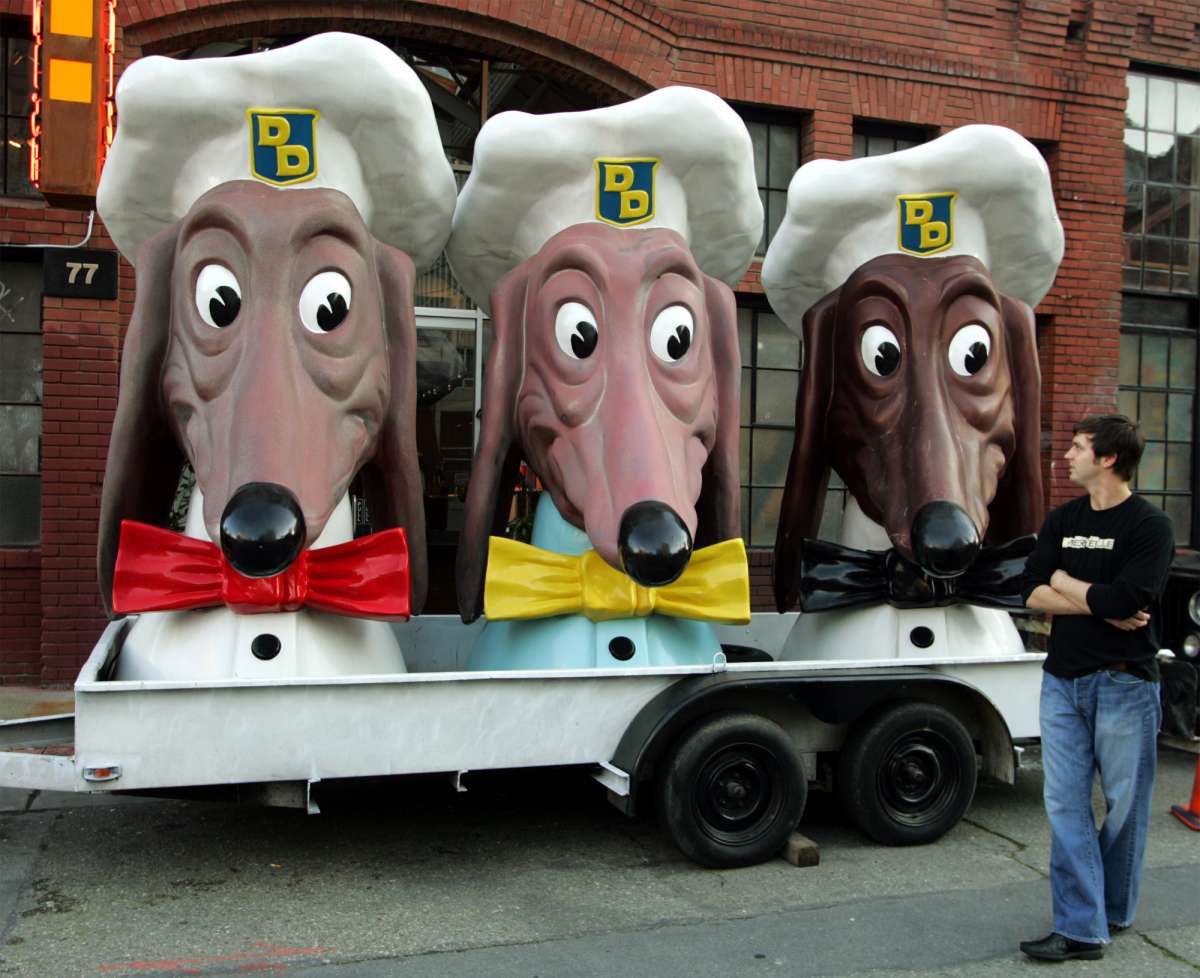 Nick Jumonville de Nueva Orleans mira a un trío de cabezas de Doggie Diner estacionadas afuera de una galería de arte y un bar de vinos para la inauguración de una exhibición en San Francisco, el miércoles 12 de enero de 2005. Los personajes alguna vez fueron las figuras decorativas encima de las dos docenas de Doggie Diner calientes. puestos de perros que existieron desde 1949 hasta 1986 en el área de la Bahía de San Francisco.