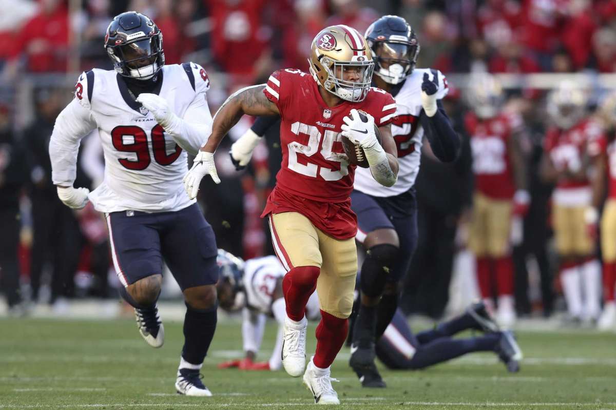 El running back Elijah Mitchell (25), de los 49ers de San Francisco, deja atrás al defensive tackle Ross Blacklock (90) y al defensive end Jonathan Greenard, de los Texans de Houston, en partido de NFL en Santa Clara, California, el domingo 2 de enero de 2022. (AP Foto/Jed Jacobsohn)