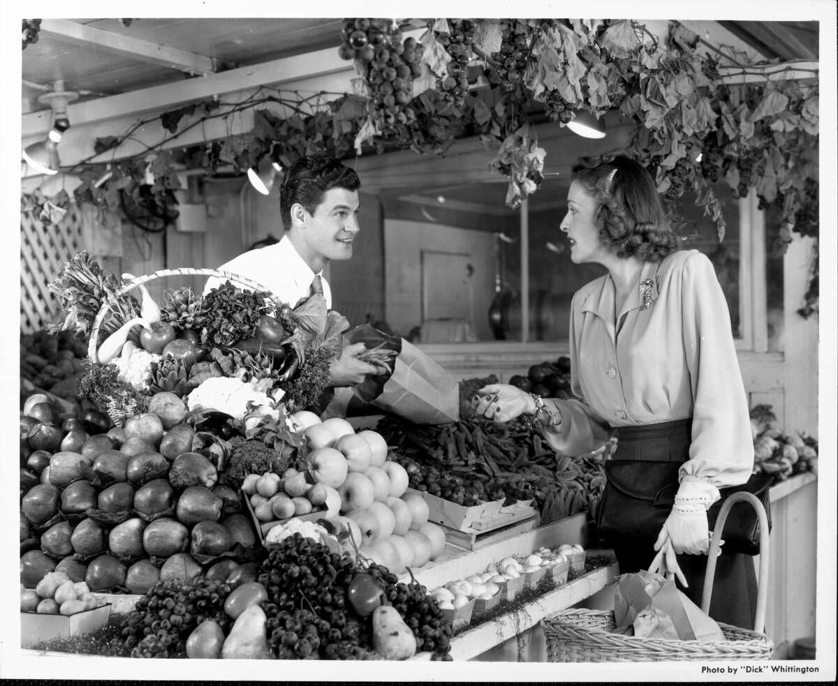 Un tendero ayuda a un comprador en un mercado de California en la década de 1940.