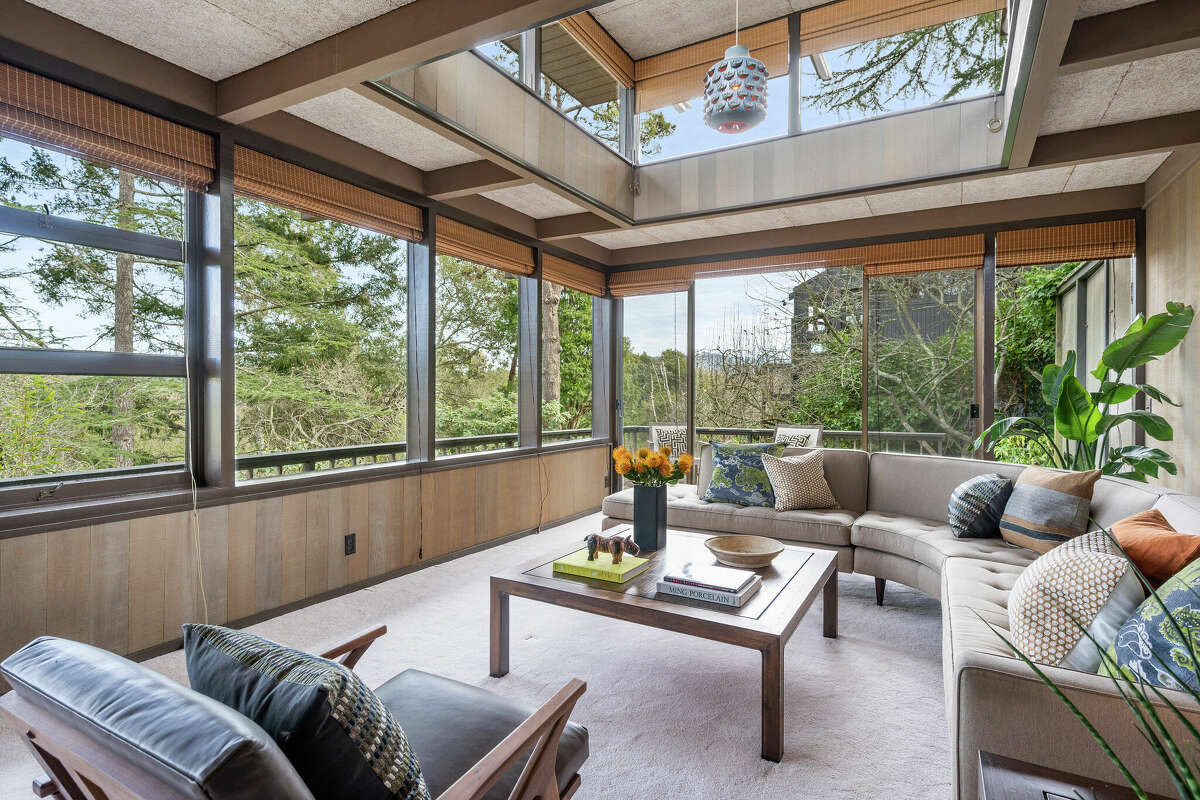 Esta sala de estar enmarca la vista boscosa y deja entrar un torrente de luz natural. 