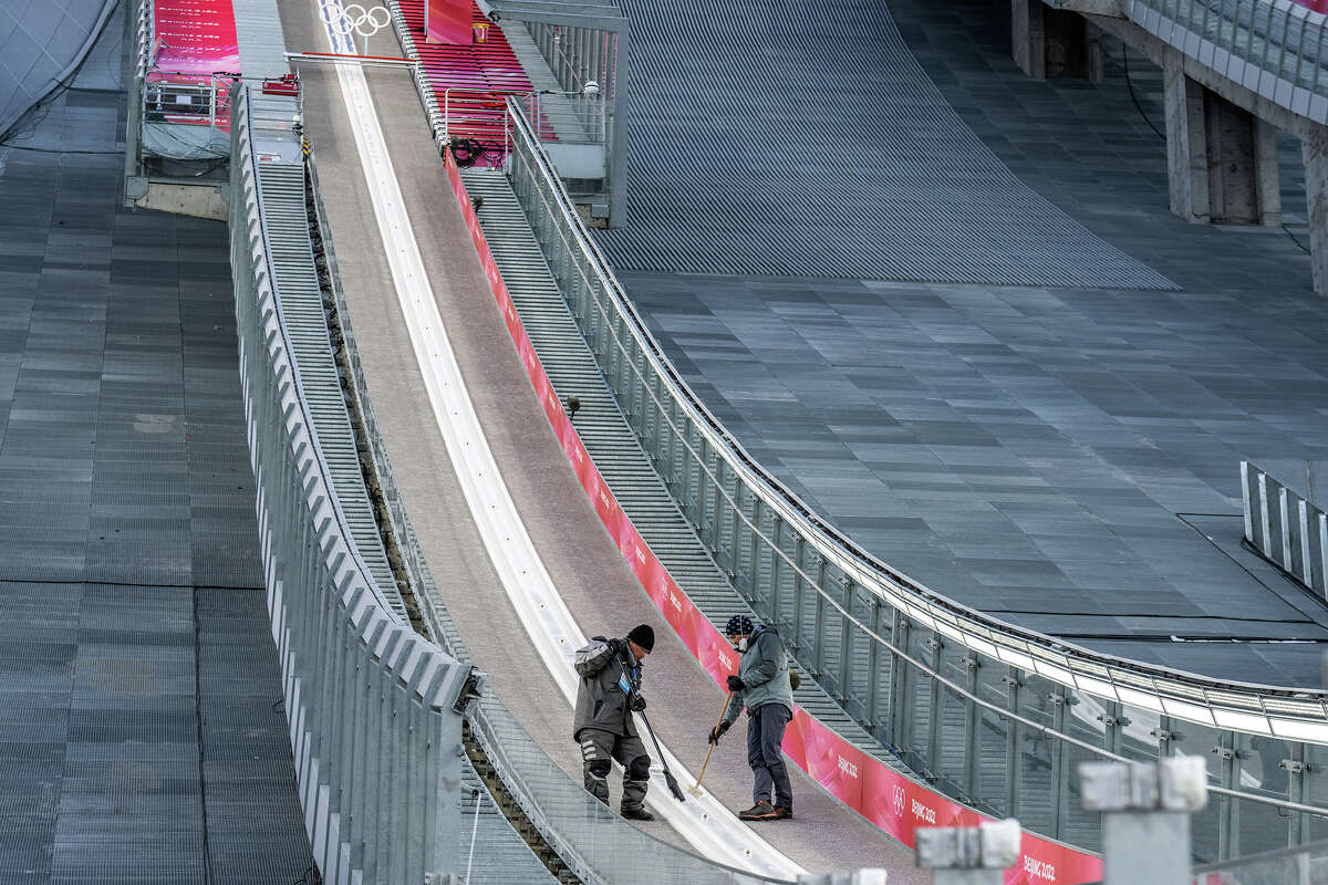 El personal barre y revisa la pendiente antes de la competencia en el Centro Nacional de Salto de Esquí el 7 de febrero en Zhangjiakou, China. Las competencias que se llevarán a cabo durante los Juegos Olímpicos de Invierno de Beijing 2022 se realizarán en su totalidad sobre nieve artificial creada por una serie de procesos, incluida la inundación de lechos de ríos secos y el desvío de suministros de agua. 