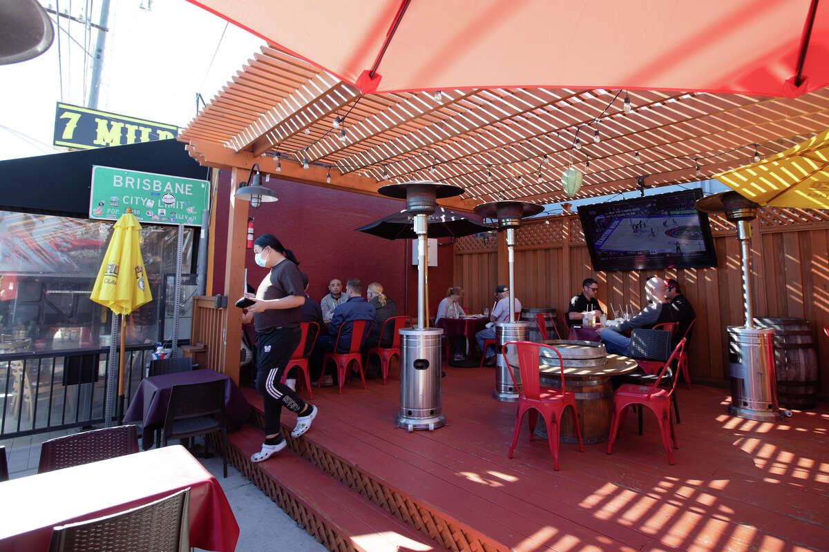 Los clientes pasan el rato en el patio al aire libre del restaurante y bar 7 Mile House en Brisbane, California, el 10 de febrero de 2022. El establecimiento celebró recientemente su 164 aniversario.