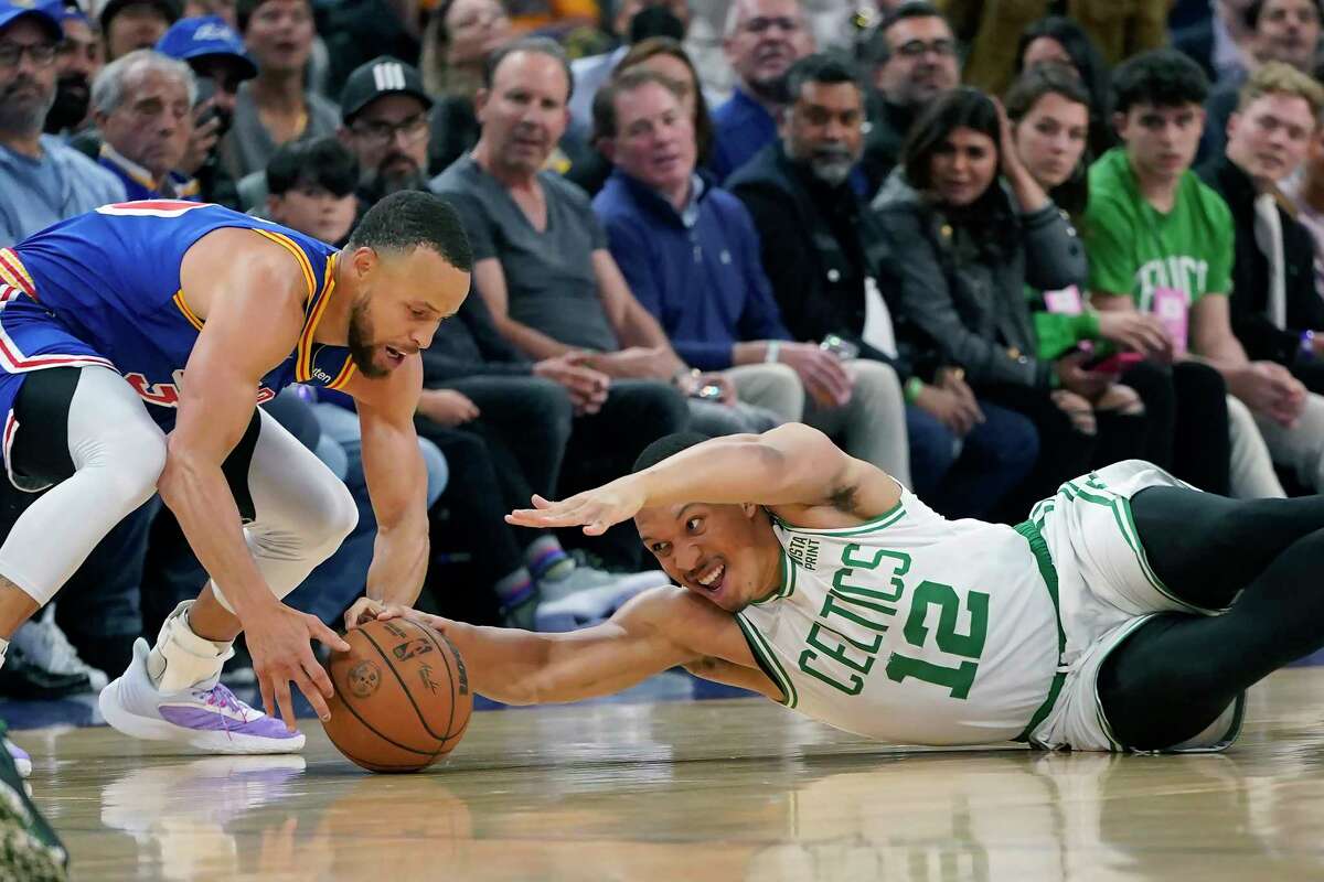El escolta de los Golden State Warriors, Stephen Curry, a la izquierda, alcanza el balón junto al alero de los Boston Celtics, Grant Williams, durante la primera mitad de un partido de baloncesto de la NBA en San Francisco, el miércoles 16 de marzo de 2022.