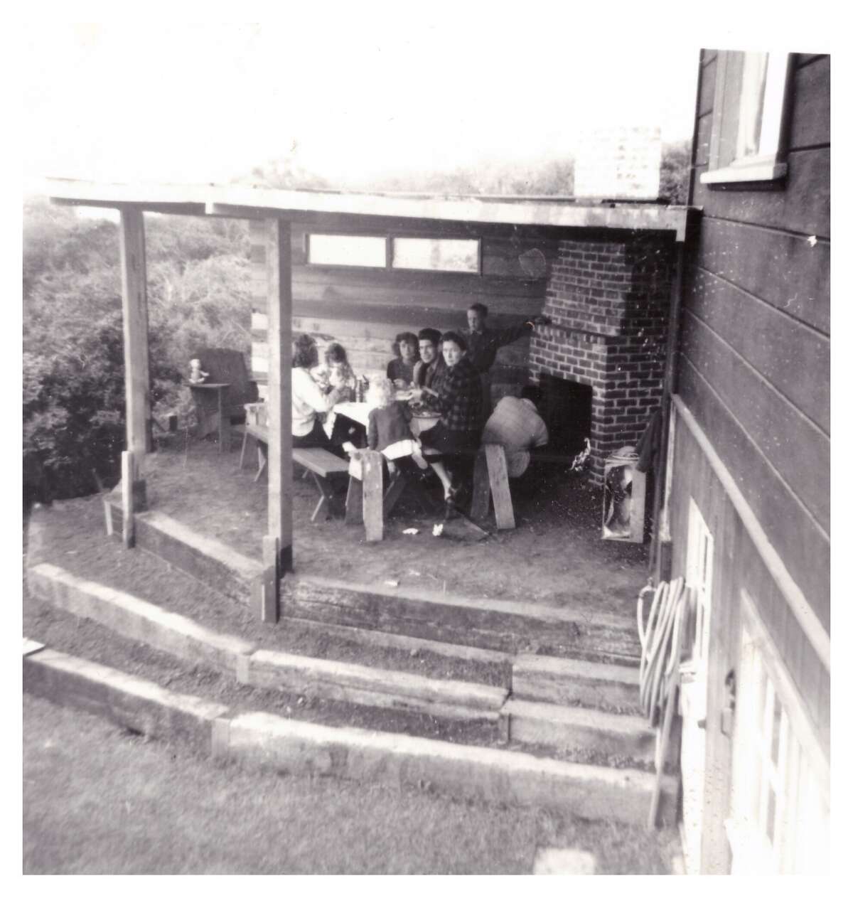 Aquí hay una foto antigua de la familia disfrutando de la chimenea al aire libre/patio cubierto. 