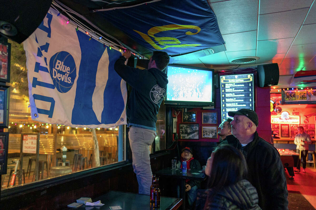 El gerente del bar Northstar Cafe, Billy Forte, cuelga la bandera de los Duke Blue Devils en preparación para el próximo juego del torneo de la NCAA, el miércoles 23 de marzo de 2022.