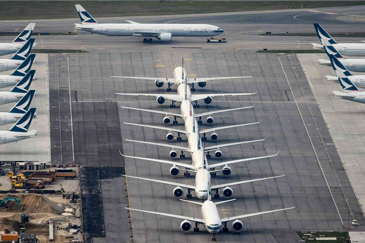 Un avión de pasajeros de Cathay Pacific se dirige a una pista el 10 de marzo de 2020, mientras se ven otros aviones pertenecientes a la aerolínea insignia local estacionados en la pista del Aeropuerto Internacional Chek Lap Kok de Hong Kong.