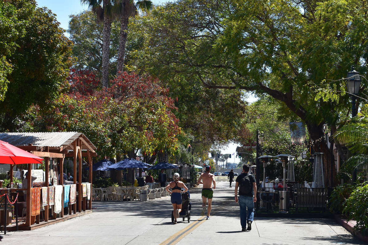 Un par de corredores y un cochecito recorren State Street en Santa Bárbara en una tarde soleada reciente entre semana. 