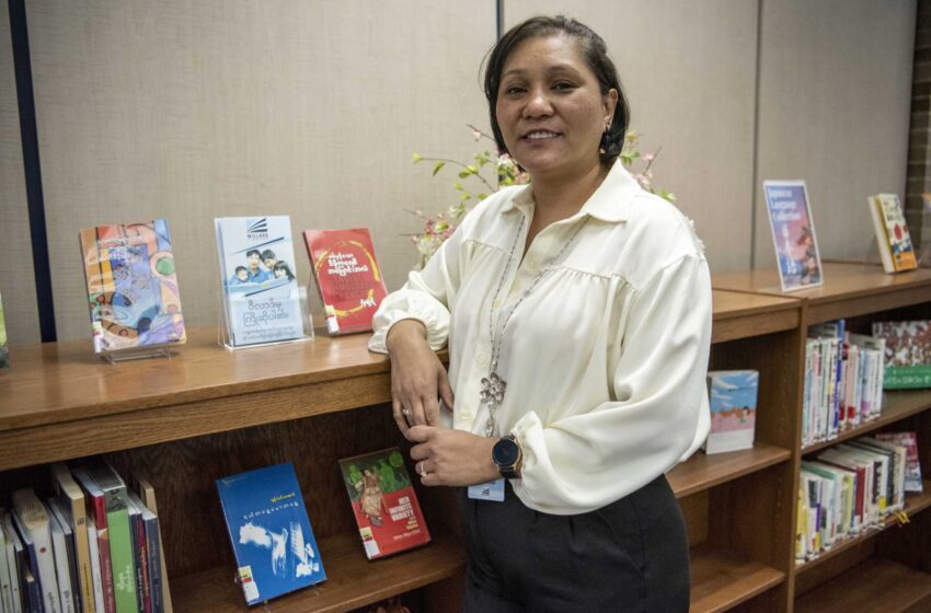  Un empleado ayuda a ampliar los libros birmanos en la biblioteca de Battle Creek