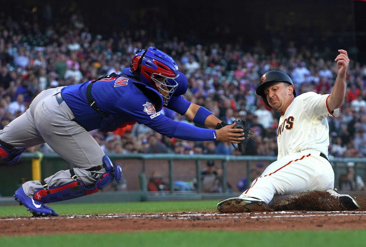 Alex Dickerson, de los Gigantes de San Francisco, anota deslizándose en el plato antes del toque de Víctor Caratini, de los Cachorros de Chicago, en la parte baja de la segunda entrada en Oracle Park el 23 de julio de 2019, en San Francisco.