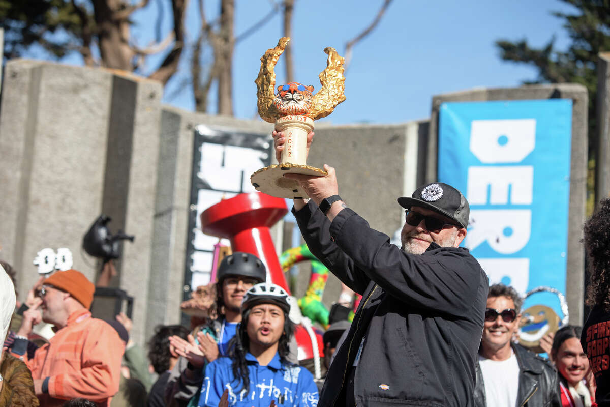 John Case sostiene el trofeo que ganó después de tener el tiempo de carrera más rápido con su corredor de caja de jabón en el SFMOMA Soapbox Derby en McLaren Park en San Francisco, California, el 10 de abril de 2022.