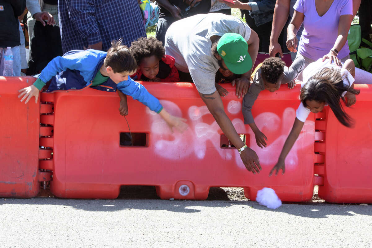 Los espectadores pasan por encima de una barrera en un trozo de algodón que voló un corredor de caja de jabón durante su carrera en el SFMOMA Soapbox Derby en McLaren Park en San Francisco, California, el 10 de abril de 2022.