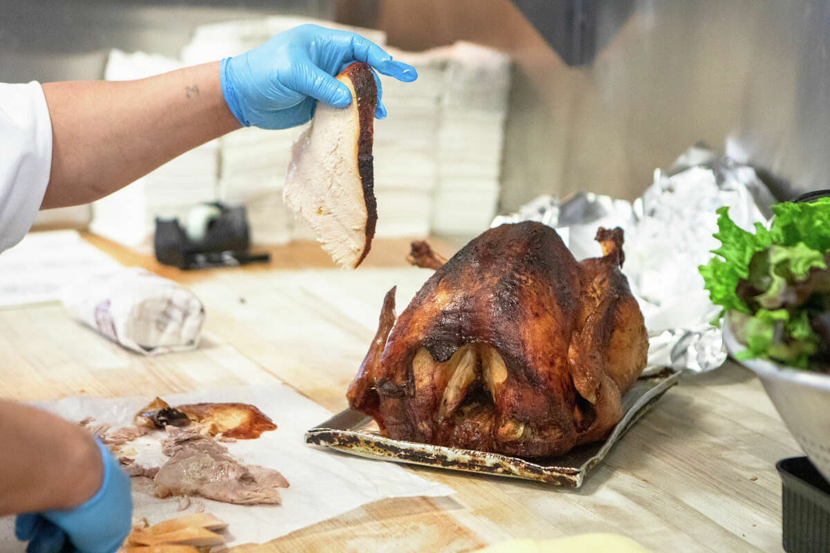 Un empleado corta un pavo para hacer un sándwich de pavo asado caliente en Arguello Market en San Francisco, California, el 10 de abril de 2022. El mercado es el autodenominado hogar del 