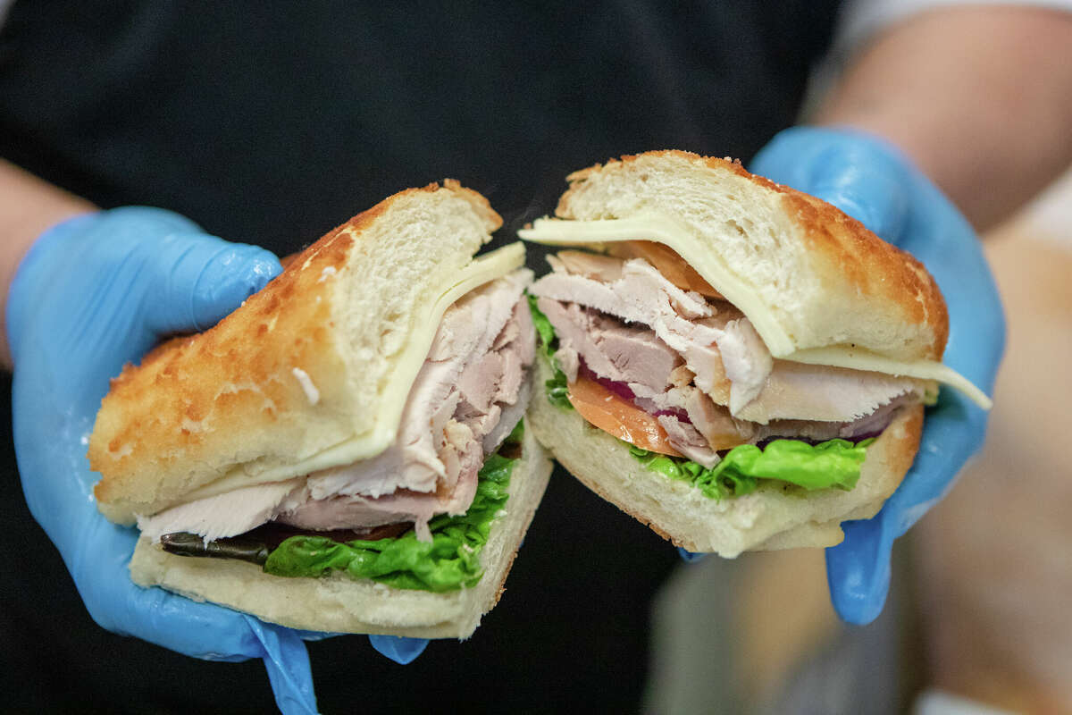 Un empleado sostiene un sándwich de pavo asado caliente en Argüello Market en San Francisco, California, el 10 de abril de 2022. El mercado es el autodenominado hogar del 'World Famous Turkey Sandwich'.