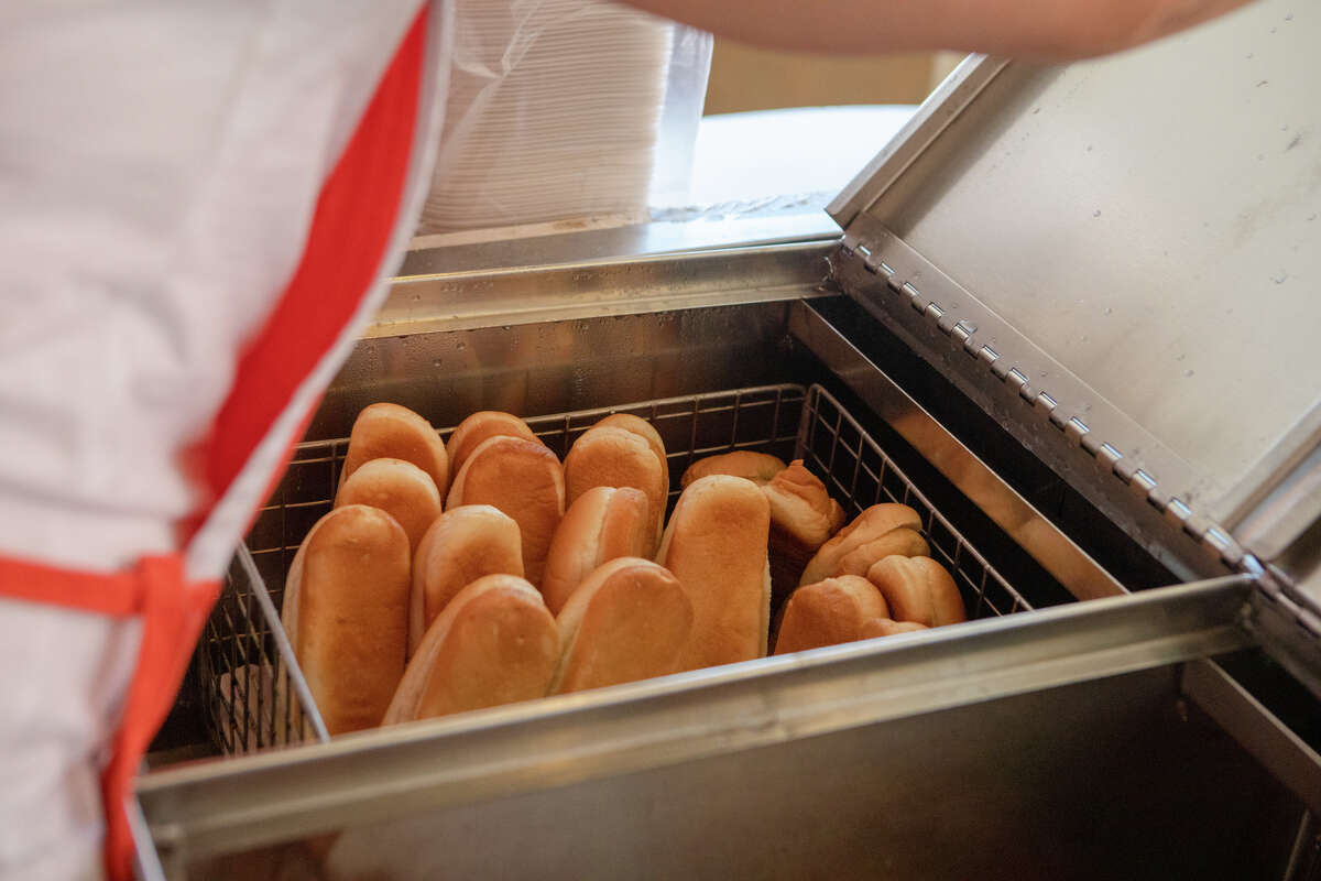 La empleada de Caspers, Veronica Palomino, saca panecillos de perritos calientes al vapor para preparar un pedido de perritos calientes en Caspers Hot Dogs en Hayward, California, el 7 de abril de 2022.