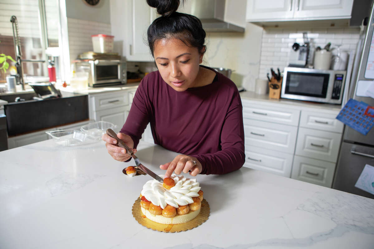 Monique Feybesse coloca un hojaldre choux sobre una tarta St. Honore en la cocina de su casa en Vallejo, California, el 8 de abril. Ella y su esposo Paul hornean todos los pasteles y panes creados por su empresa Tarts de Feybesse.