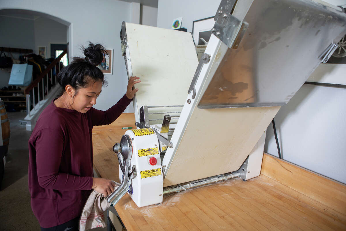 Monique Feybesse explica cómo funciona su máquina laminadora de masa en la cocina de su casa en Vallejo, California, el 8 de abril de 2022. Monique y su esposo Paul hornean ellos mismos todos los pasteles y panes creados por su empresa Tarts de Feybesse.