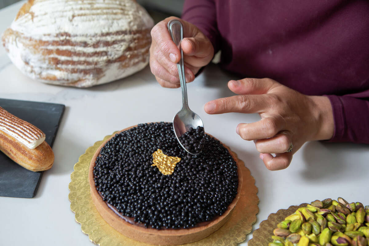 Monique Feybesse pone los toques finales a un Caviar de Chocolate" tarta en la cocina de su casa en Vallejo, California, el 8 de abril de 2022. La "caviar" son en realidad pequeños trozos de chocolate. Monique y su esposo Paul hornean ellos mismos todos los pasteles y panes creados por su empresa Tarts de FeyBesse.