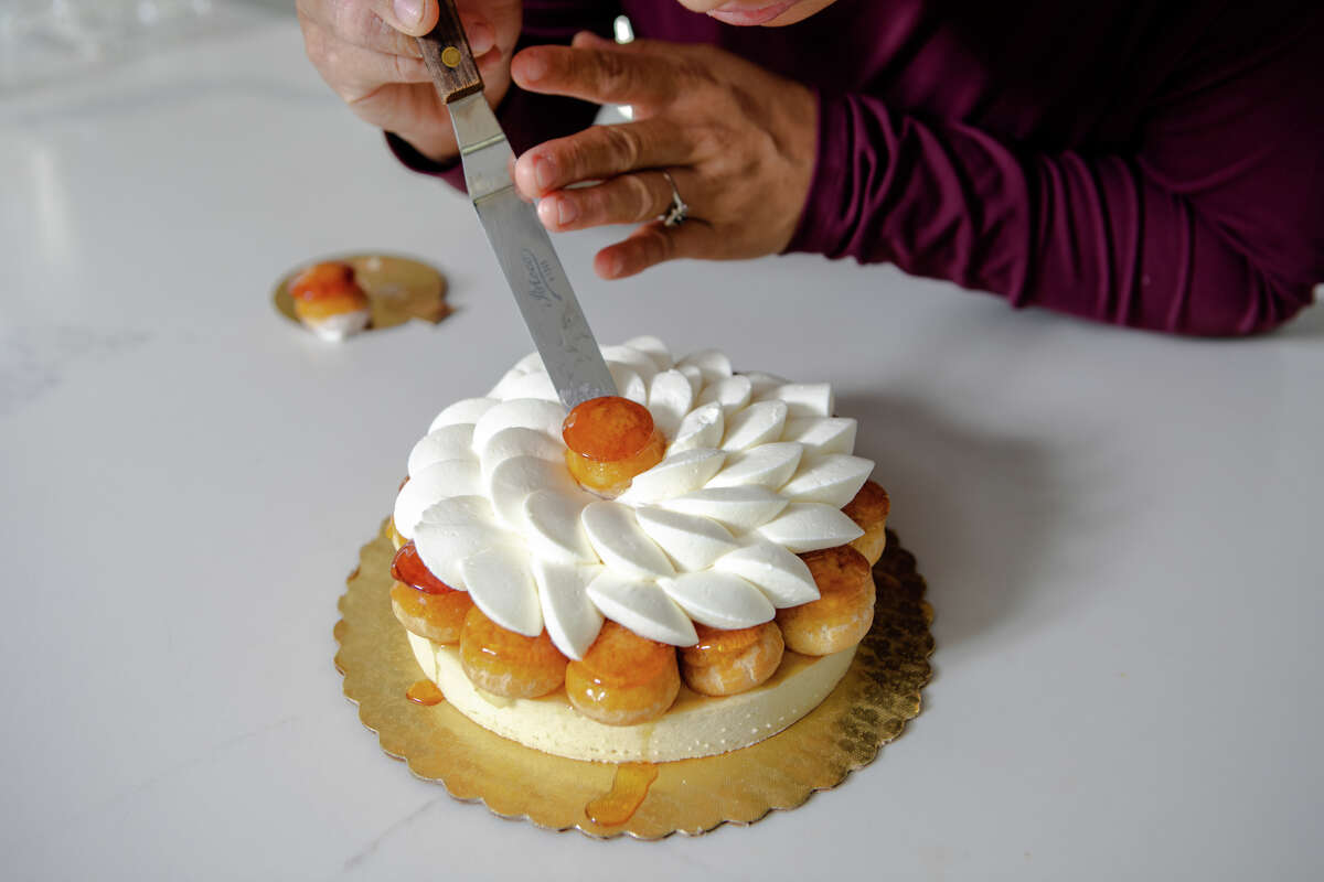 Monique Feybesse coloca un hojaldre de choux sobre una St. Honor® Tart en la cocina de su casa en Vallejo, California, el 8 de abril de 2022. Monique y su esposo Paul hornean ellos mismos todos los pasteles y panes creados por su empresa Tarts de Feybesse.