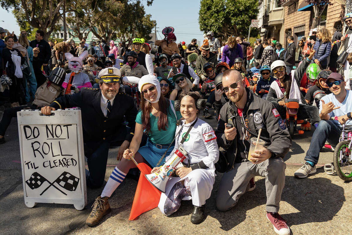 El organizador del evento, Frog Gilmore, en el centro con un megáfono, posa con los participantes en la línea de salida del evento Trae tu propia rueda grande de este año en Vermont y las calles 20th, en San Francisco.