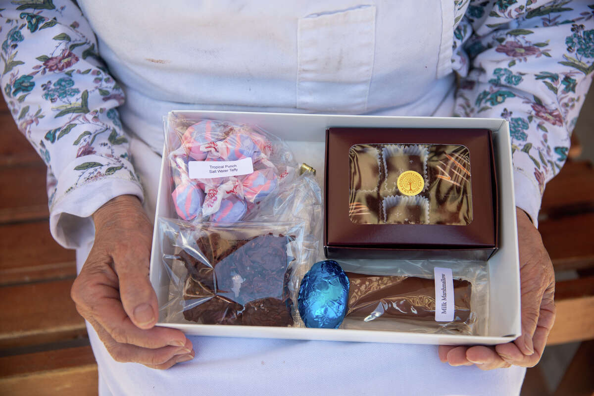 La propietaria Irene Preston posa con una 'caja de rescate' de chocolate en Preston's Candy & Ice Cream en Burlingame, California, el 10 de mayo de 2022. Las cajas son para ayudar a las ventas en la tienda de 75 años que ha sufrido durante el COVID- 19 pandemia.