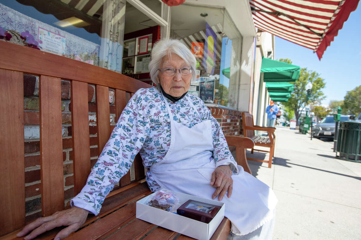 La propietaria Irene Preston posa con una 'caja de rescate' de chocolate en Preston's Candy & Ice Cream en Burlingame, California, el 10 de mayo de 2022. Las cajas son para ayudar a las ventas en la tienda de 75 años que ha sufrido durante el COVID- 19 pandemia.