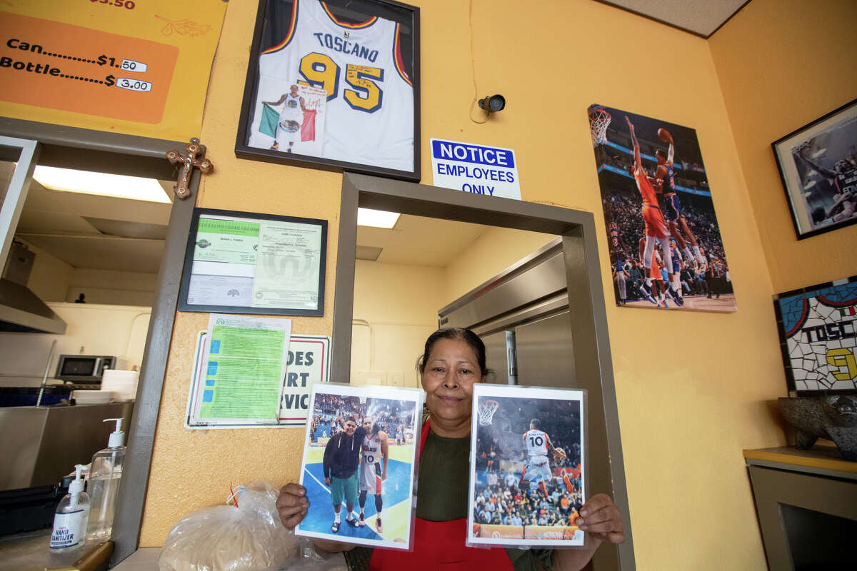 Taqueria La Mejor María Pardo posa con fotografías de su nieto, el jugador de los Warriors Juan Toscano-Anderson, en Oakland, California, el 5 de mayo de 2022.
