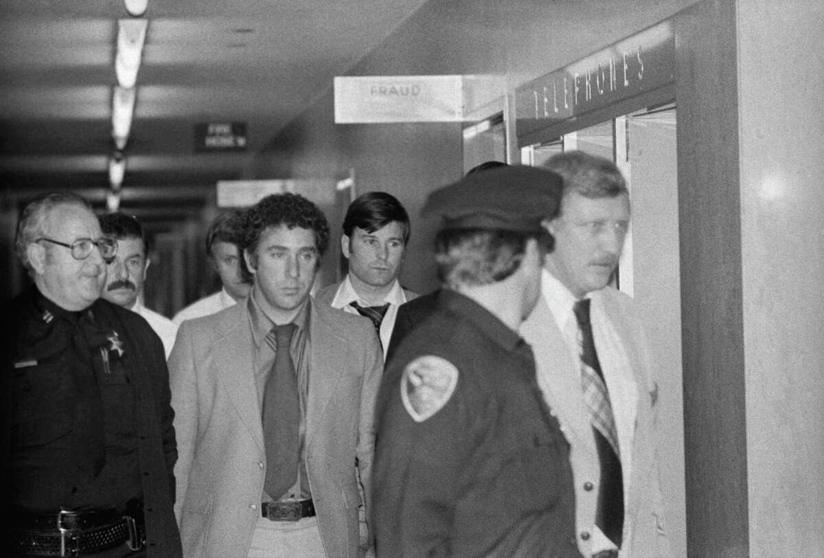 Dan White (directamente debajo del letrero "Fraude") es conducido por agentes de policía hacia un ascensor de la cárcel en el Salón de Justicia después de matar al alcalde George Moscone y al supervisor Harvey Milk.