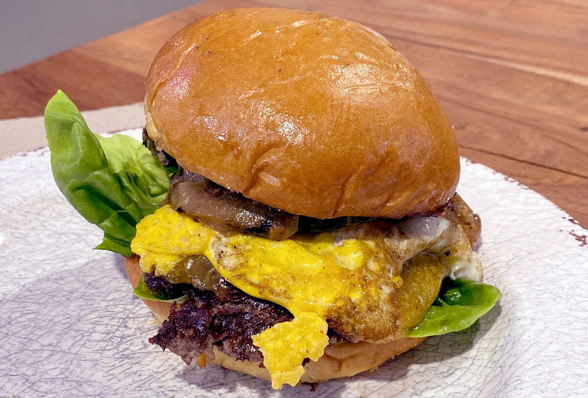 La hamburguesa con queso de Teranga se apila con un huevo duro frito, dos empanadas de carne molida, queso cheddar y se termina con un ketchup de tomate dulce hecho en casa que une toda la hamburguesa.