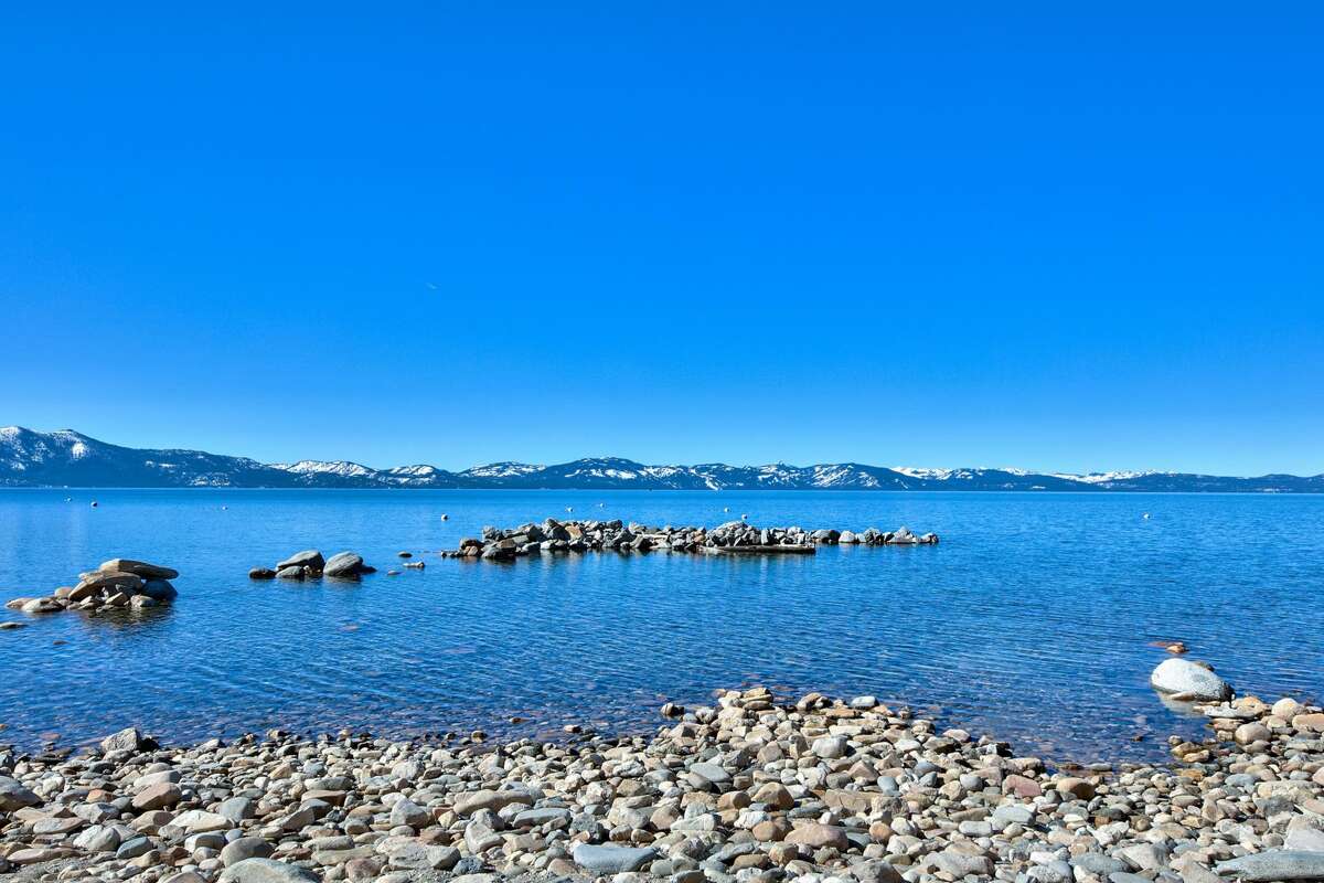 Desde la playa, el azul cristalino del lago Tahoe brinda un resplandor azulado a las montañas más allá. 