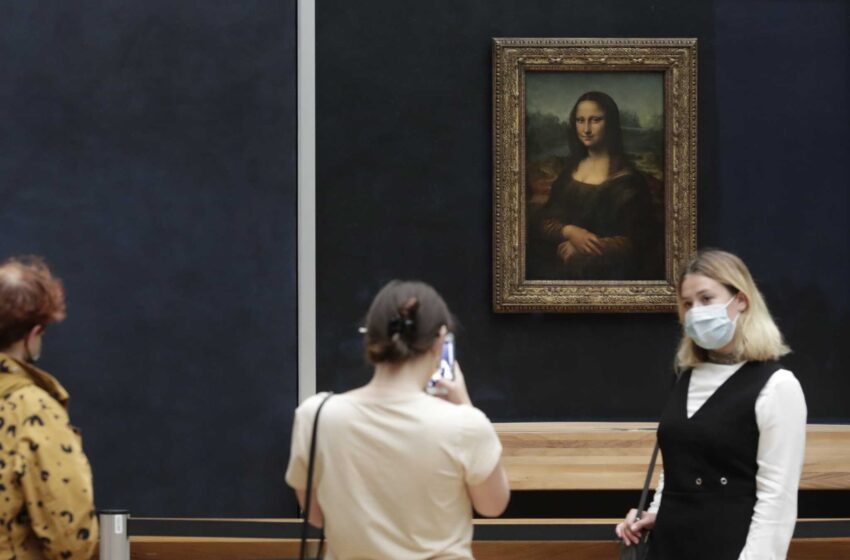  Un hombre con peluca lanza un pastel al cristal que protege a la Mona Lisa