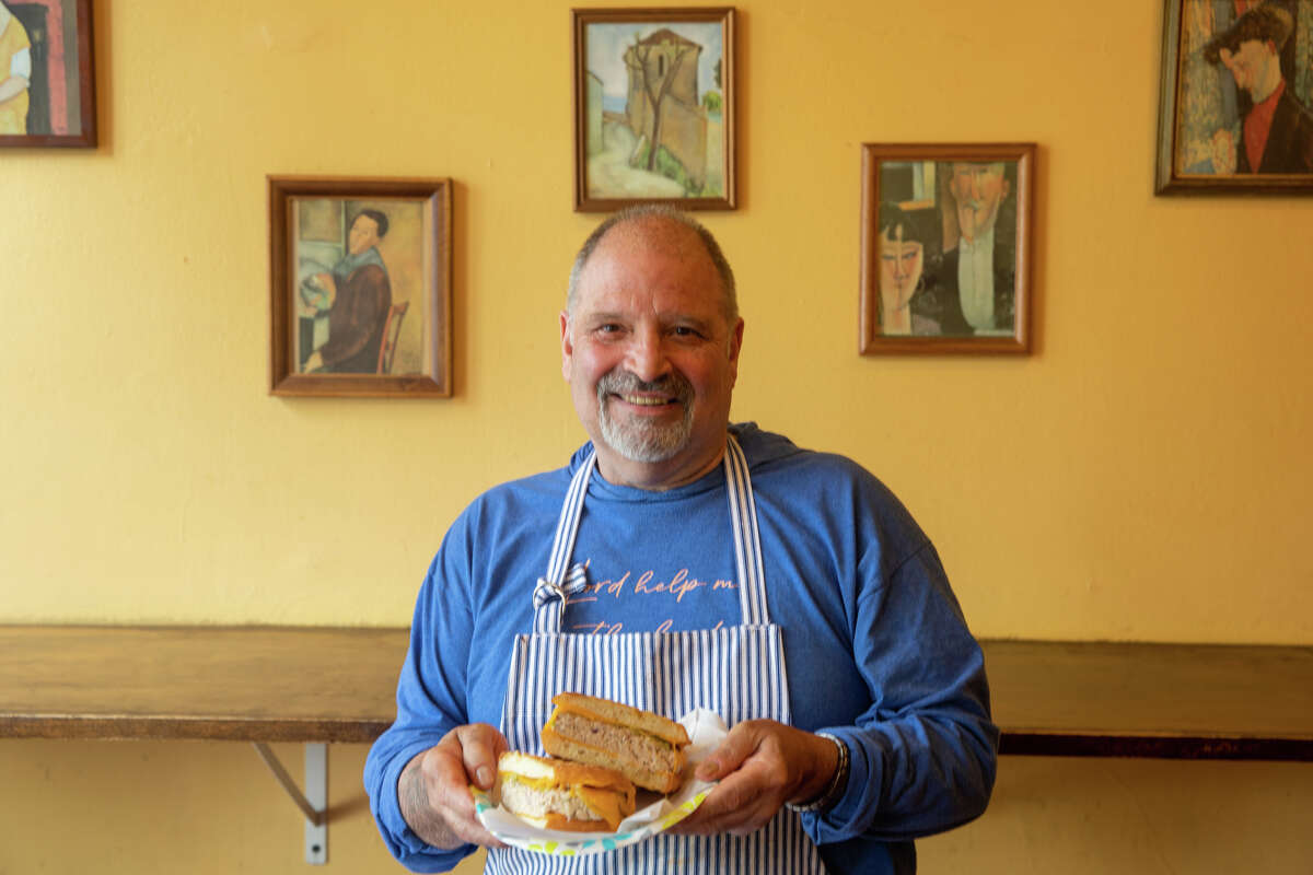 El propietario Gerry Mogg sostiene un sándwich de atún derretido en Modigliani Cafe en Oakland, California, el 3 de junio de 2022.