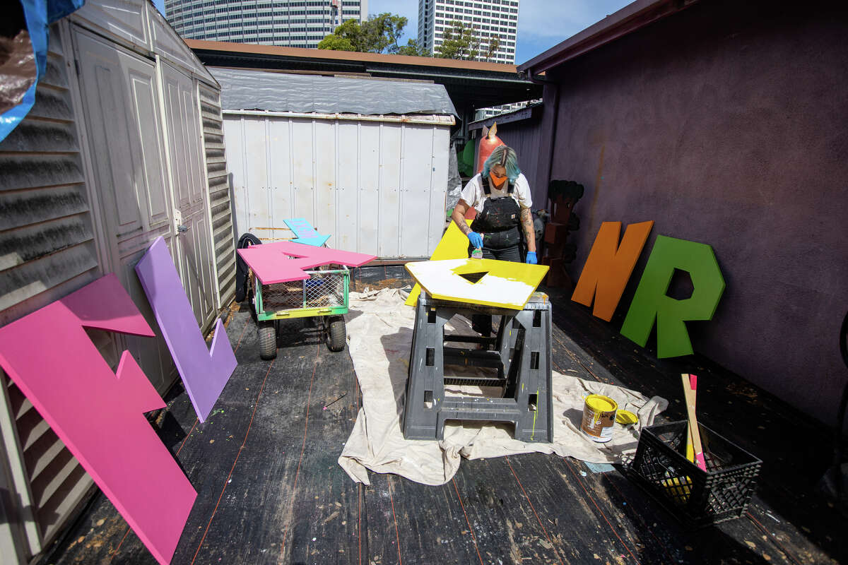 El pintor de Children's Fairyland, Ari Bird, trabaja pintando el letrero del parque temático en el espacio de trabajo del departamento de arte en Oakland, California, el 8 de junio de 2022. La directora de arte y restauración Shannon Taylor (sin foto) y Bird trabajan para restaurar y mantener el parque temático paseos y atracciones en plena forma.