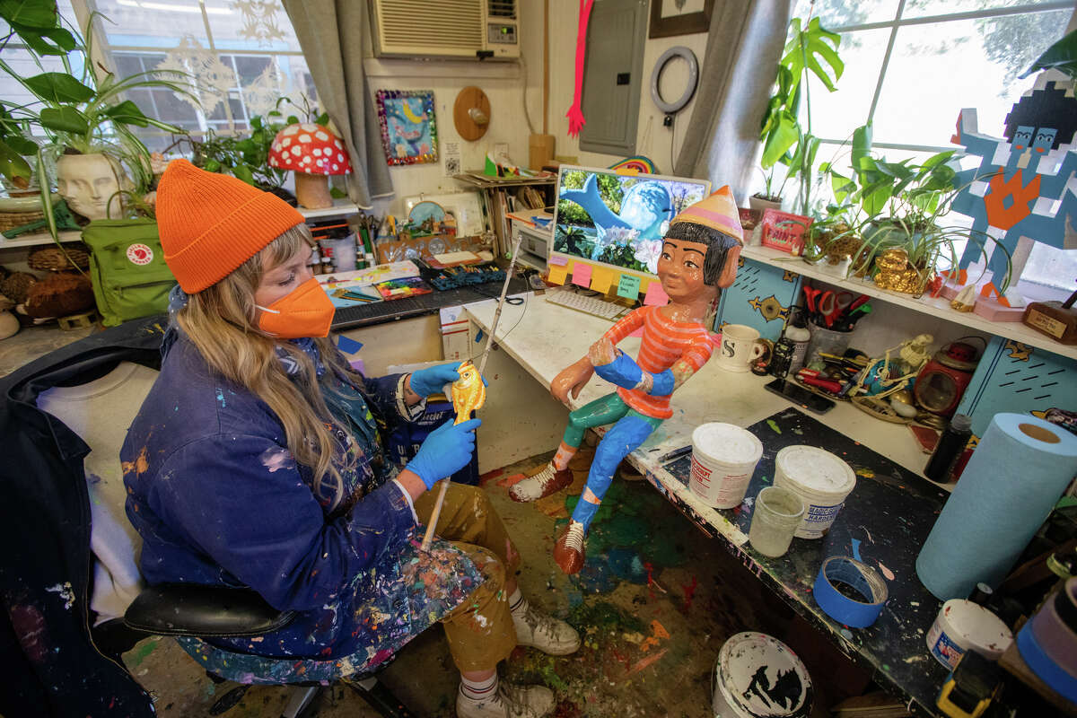 La directora de arte y restauración de Children's Fairyland, Shannon Taylor (con gorra naranja), aplica un poco de arcilla para moldear a un duende que necesita reparaciones en el espacio de trabajo del departamento de arte en Oakland, California, el 8 de junio de 2022. Allí ayuda a restaurar y mantener el tema. paseos y atracciones del parque en plena forma.