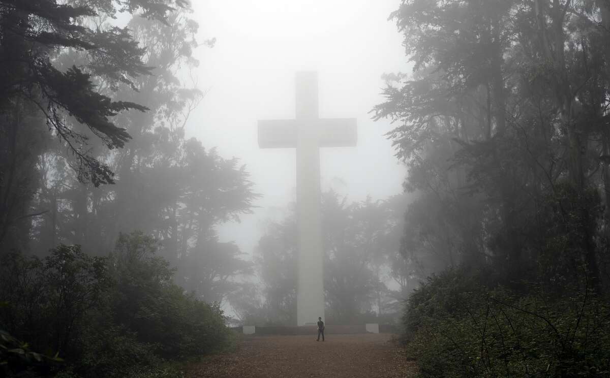 Un visitante camina bajo una cruz cubierta de niebla en el Monte Davidson, el viernes 11 de agosto de 2017, en San Francisco.