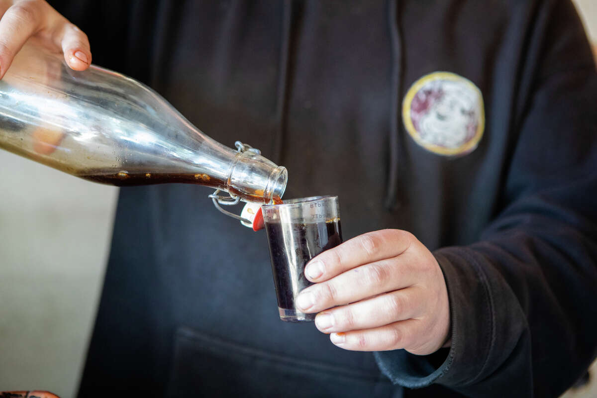 Nick Floulis vierte parte de su cerveza fría para agregarla al agua de coco en Hole in the Wall Coffee en North Beach en San Francisco, California, el 23 de junio de 2022.