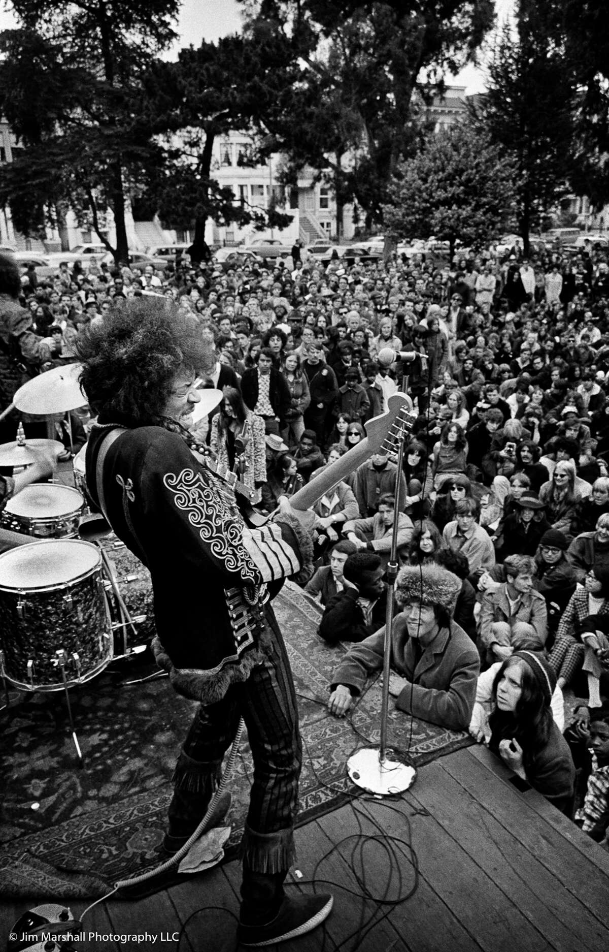 Jimi Hendrix actuando en un concierto gratuito en el Panhandle, en San Francisco, el 25 de junio de 1967. Jeffrey McMeans, quien llevó a Hendrix al espectáculo ese día, se puede ver apoyado en el escenario con su babushka casera: "Pensé para mis adentros: 'Yo lo traje aquí, voy a acercarme lo más posible'."