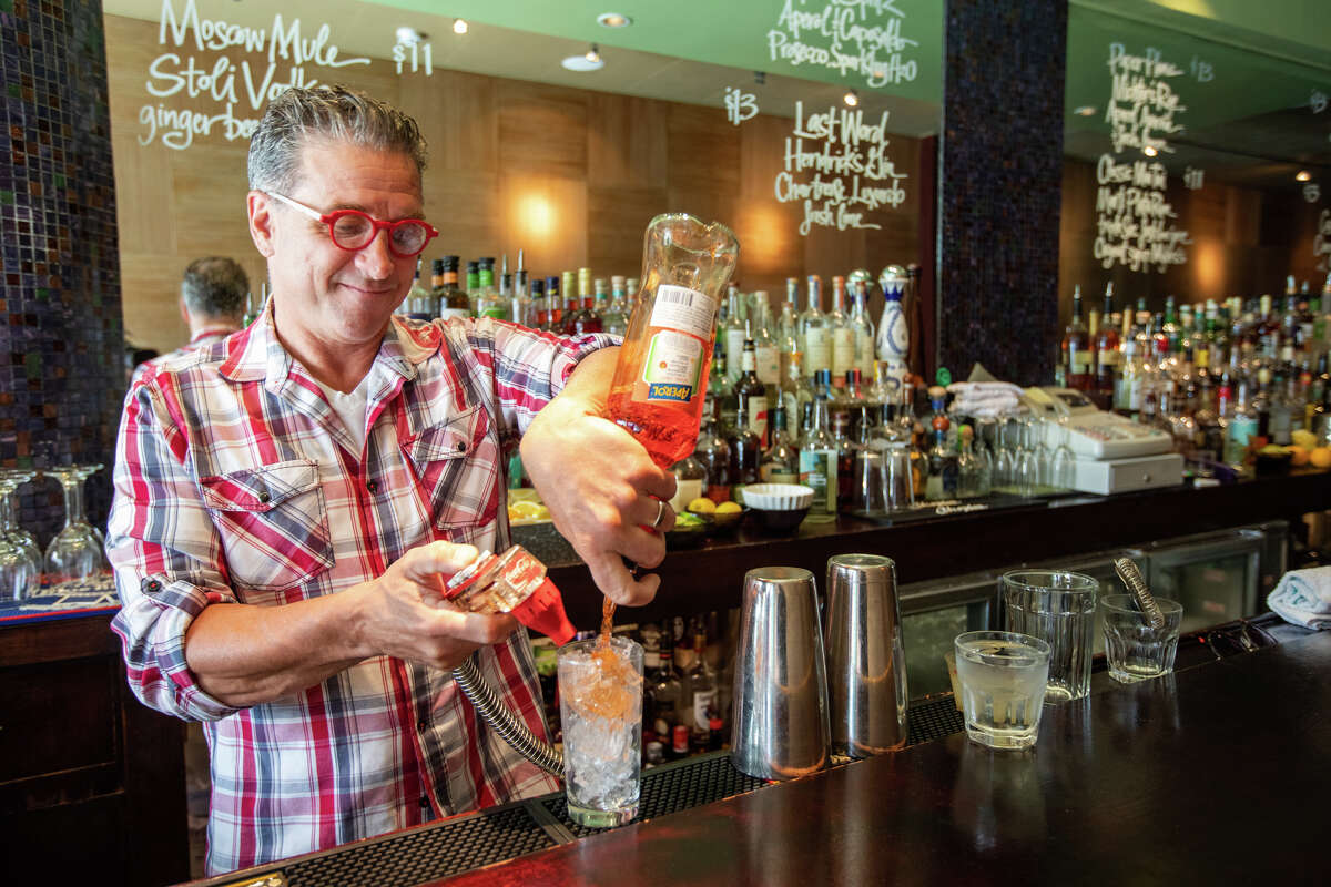 Sebastian Scala, prepara una bebida detrás de la barra del bar en Tony Niks en San Francisco, California, el 7 de julio de 2022. Scala, patrón y gerente desde hace mucho tiempo, es el nuevo propietario de Tony Niks, un bar antiguo en el corazón de Playa Norte. Se compromete a preservar su legado.