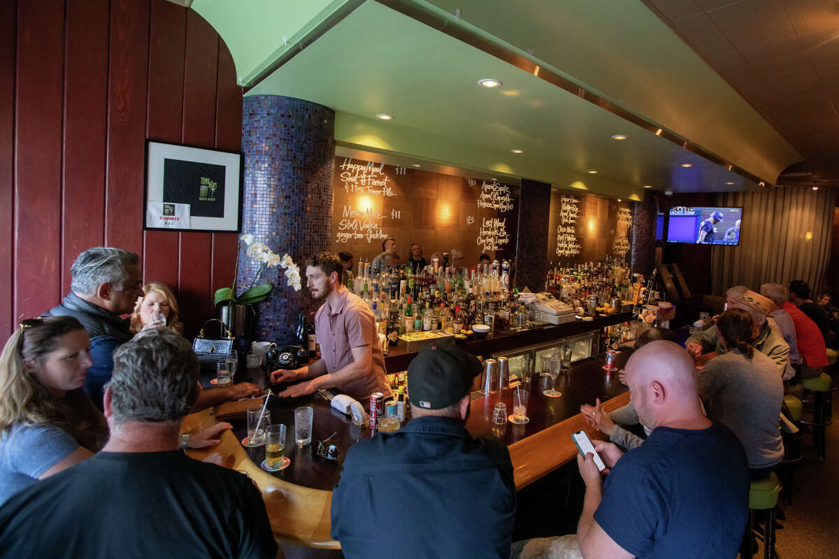 El cantinero Ian Whittaker habla con los clientes en la barra de Tony Niks en San Francisco, California, el 7 de julio de 2022. Scala, patrón y gerente desde hace mucho tiempo, es el nuevo propietario de Tony Niks, un bar antiguo en el corazón de Playa Norte. Se compromete a preservar su legado.