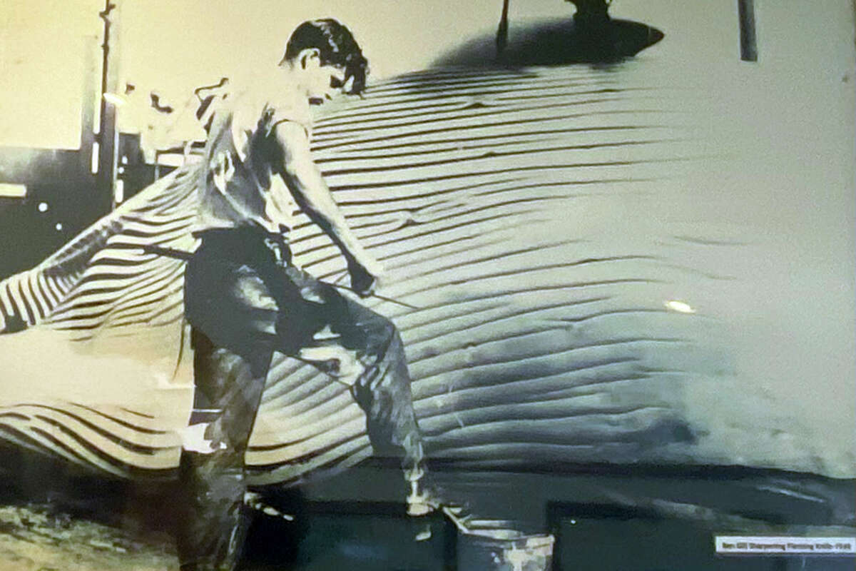 Esta fotografía de Bennie Gill se exhibe en Gill's by the Bay, que abrió con su esposa en la década de 1990. En la foto, está trabajando como desollador jefe en la estación ballenera de Fields Landing en la década de 1940.