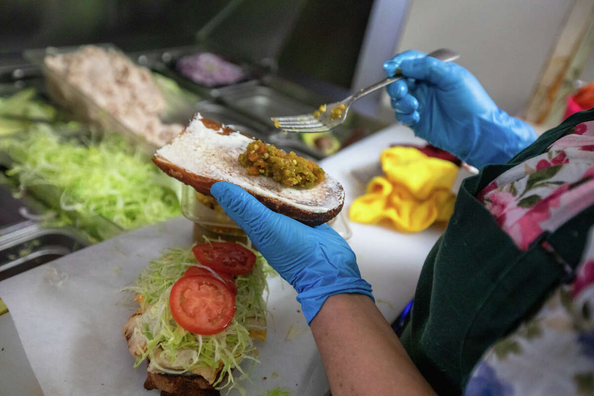 La gerente de Freddie's Sandwiches, Maura Mancia, prepara un sándwich de pollo asado con queso feta detrás del mostrador de la tienda de delicatessen North Beach en San Francisco, California, el 28 de julio de 2022.