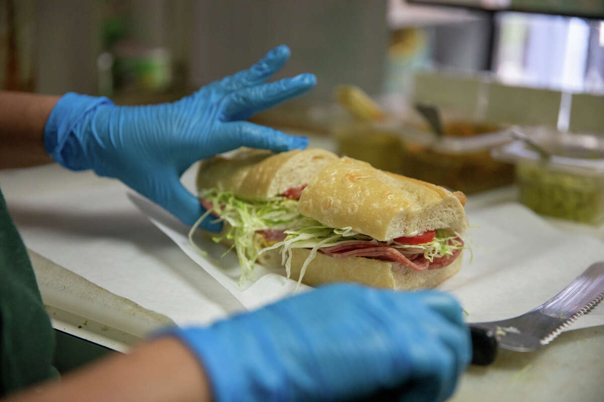 La gerente de Freddie's Sandwiches, Maura Mancia, hace un sándwich detrás del mostrador de la tienda de delicatessen North Beach en San Francisco, California, el 28 de julio de 2022.