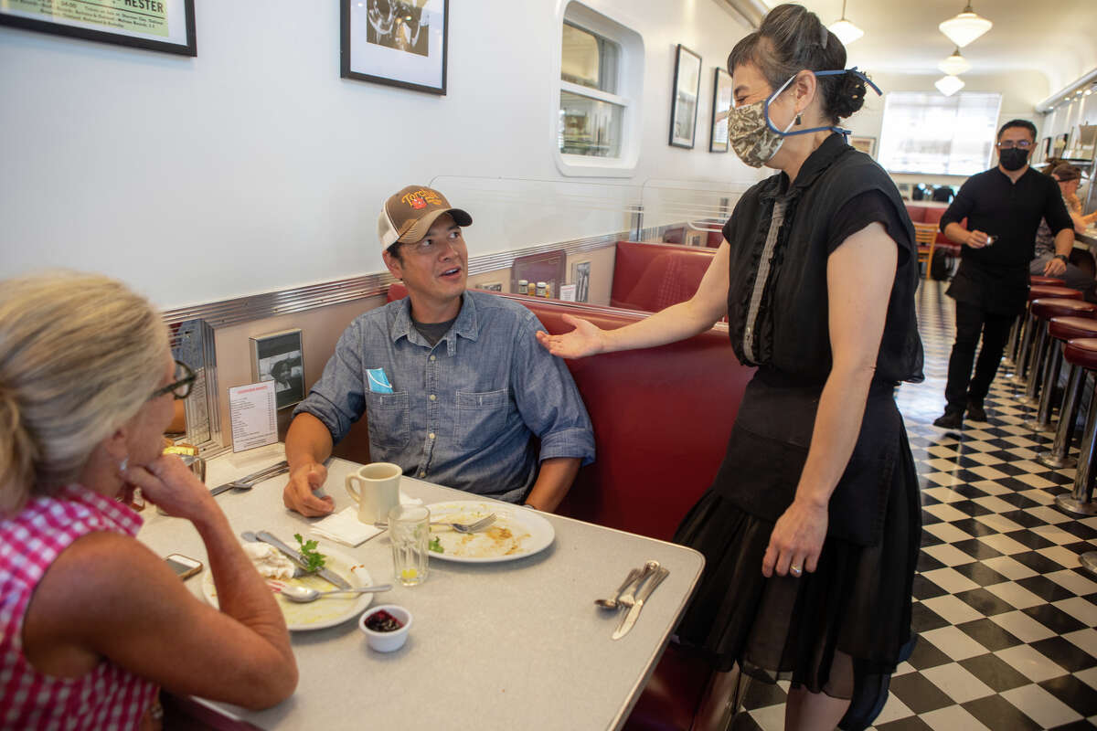 La propietaria y camarera Alice Worland habla con los clientes Kim Granger y Jim Gutiérrez en Oceanview Diner en Berkeley, California, el 9 de agosto de 2022.