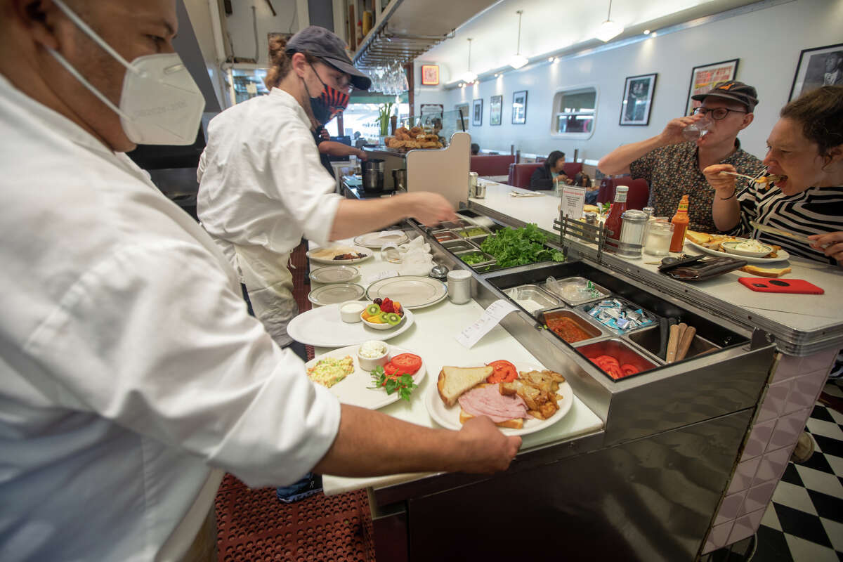 (Izquierda) Chef ErnestoCastro prepara una comida en Oceanview Diner en Berkeley, California, el 9 de agosto de 2022.