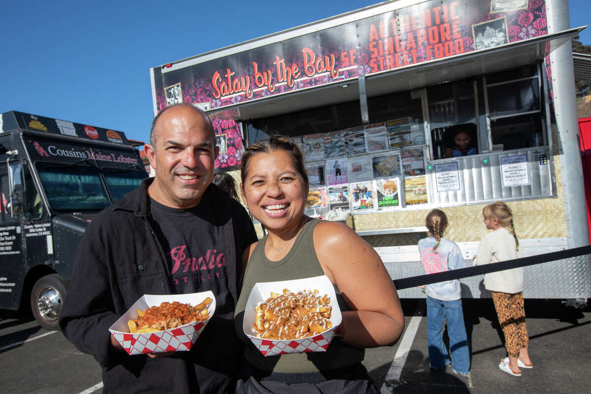 Los propietarios de Satay by the Bay, Elly y David Greenfield, sostienen sus papas fritas frías de cangrejo y papas fritas holandesas frente a su camión de comida en Off The Grid en Fort Mason en San Francisco, California, el 19 de agosto de 2022.