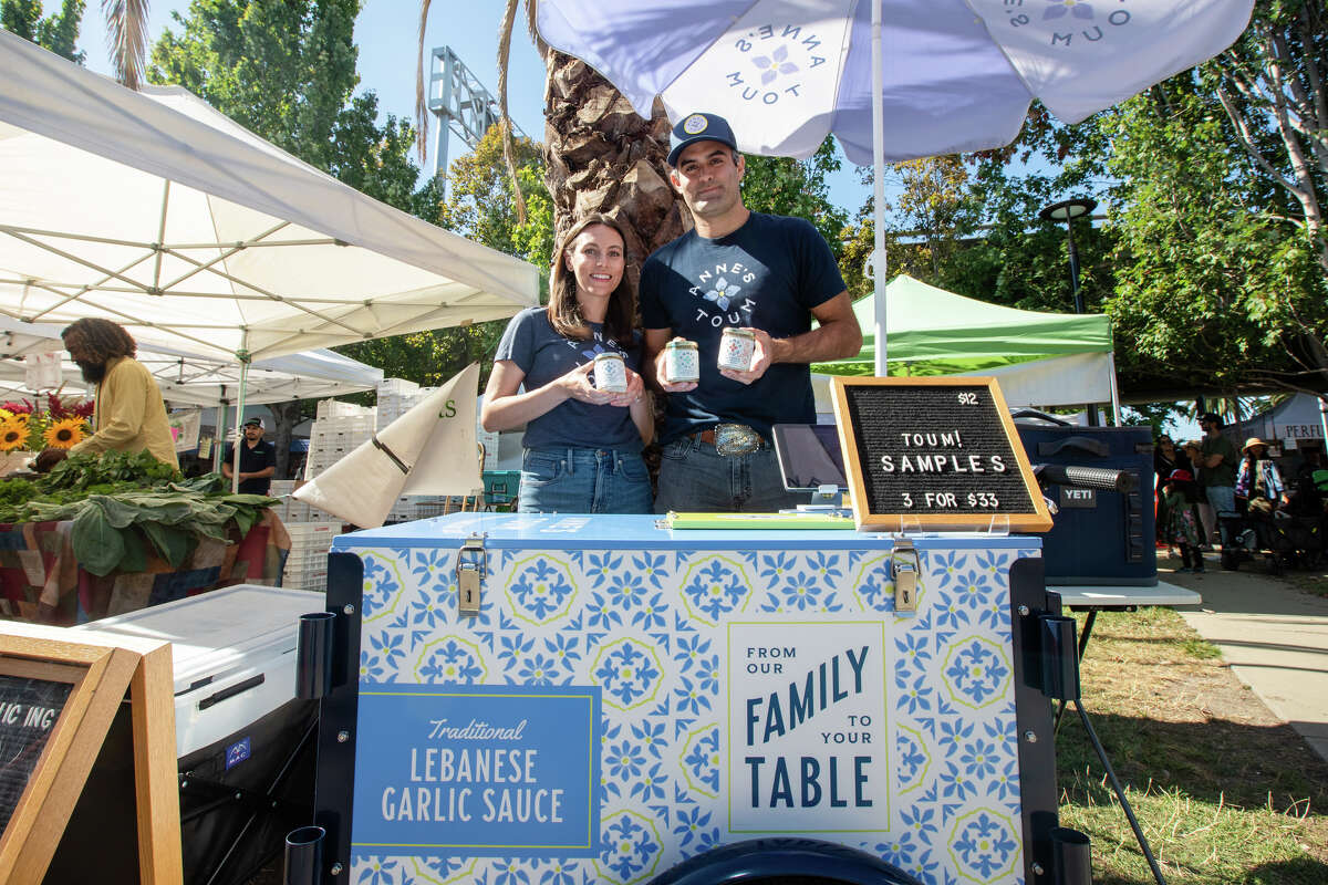 Los propietarios Katia Berberi y Steve Drapeau realizan parte de su toum en el stand de Anne's Toum en el mercado de granjeros de Grand Lake en Oakland, California, el 20 de agosto.